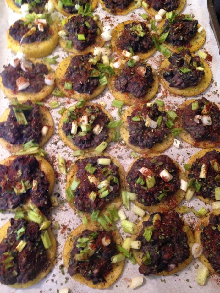 Polenta rounds topped with refried black beans, taco seasoning, green onions, and cilantro.